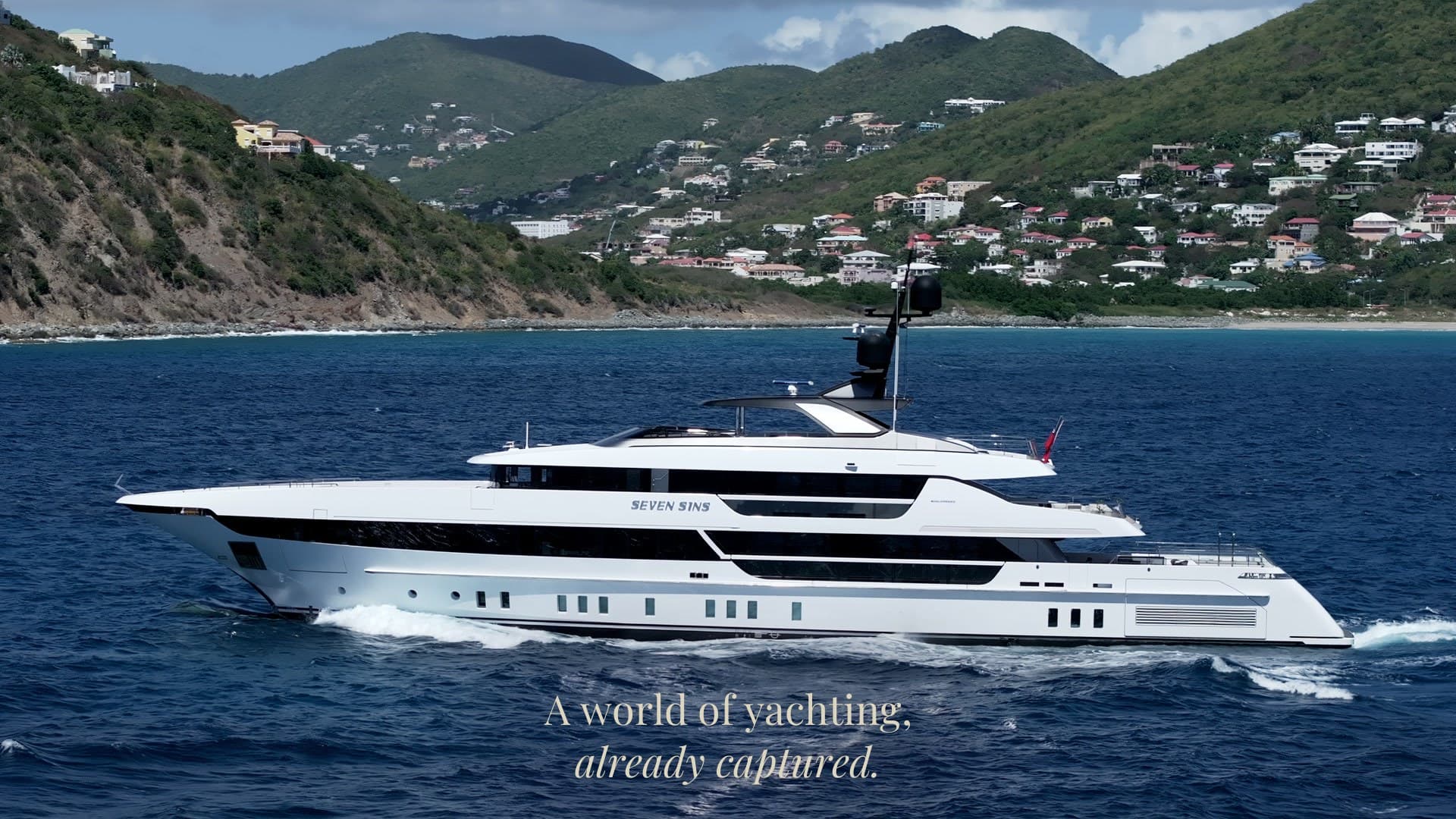A superyacht running past a green hillside, with the title “A world of yachting, already captured.”